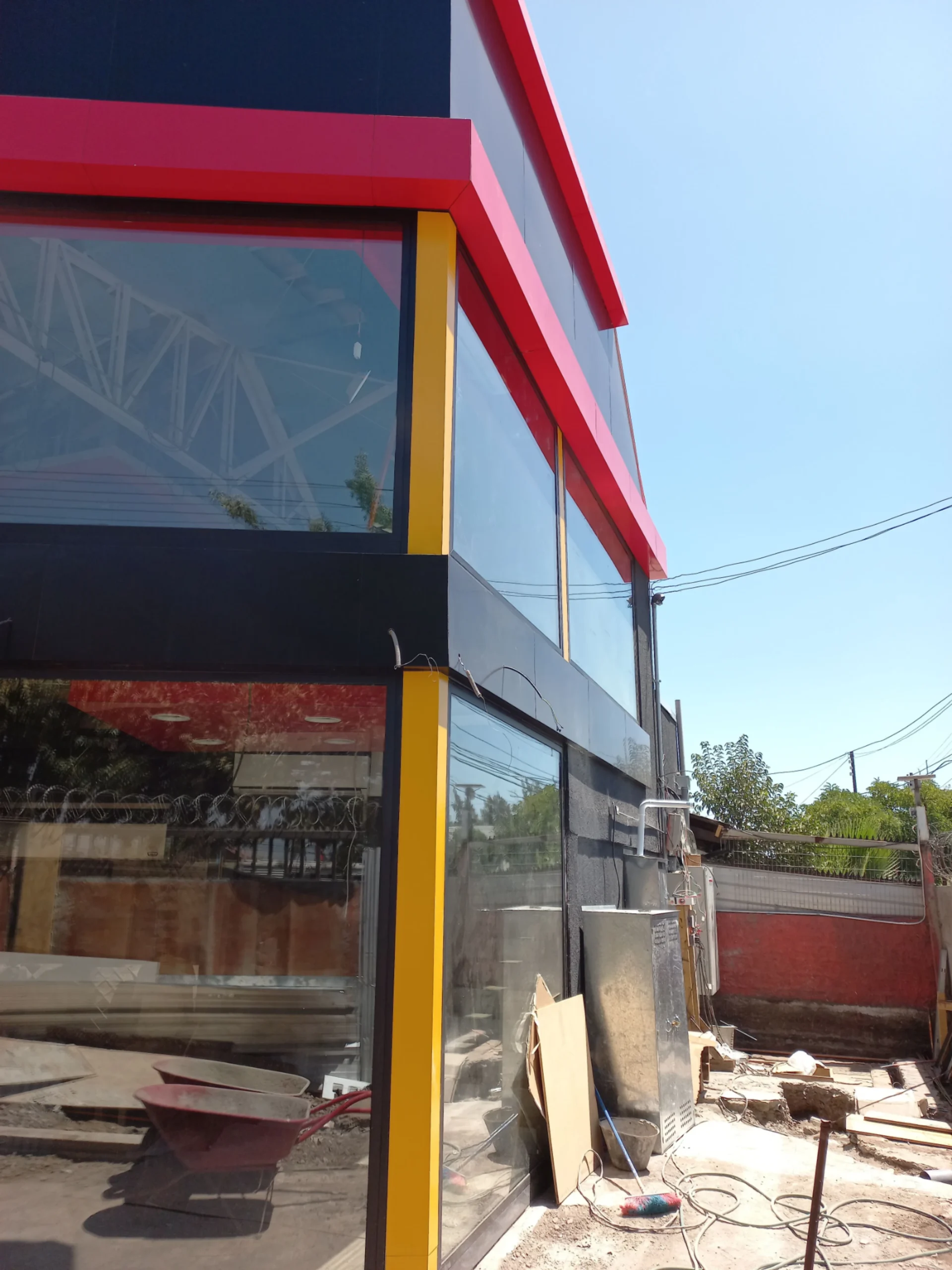 Fachada comercial en aluminio compuesto negro y rojo durante la instalación