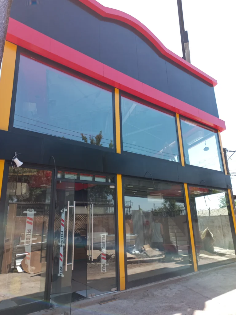Fachada de local comercial revestida en aluminio compuesto negro con franja roja